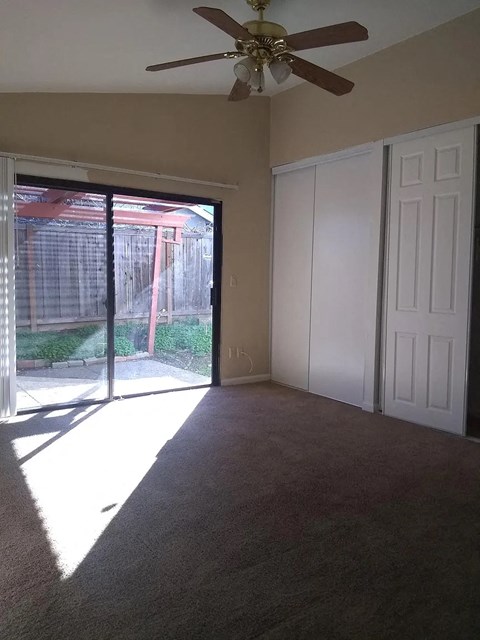 a living room with a ceiling fan and a sliding glass door