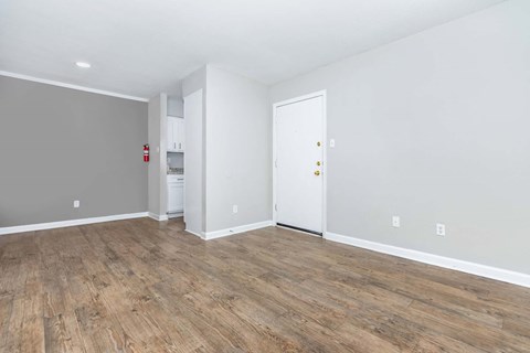 the living room and kitchen of an empty house with wood flooring