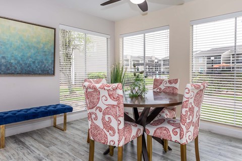 Dining room with upholstered chairs and large windows at Royal Wildewood Manor Apartments, Clute, TX