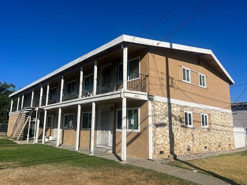 the front of a tan building with white pillars and a staircase