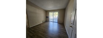 A room with wooden flooring and a sliding glass door.