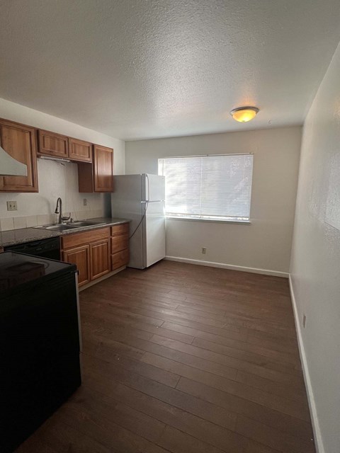 an empty kitchen with wooden floors and a refrigerator