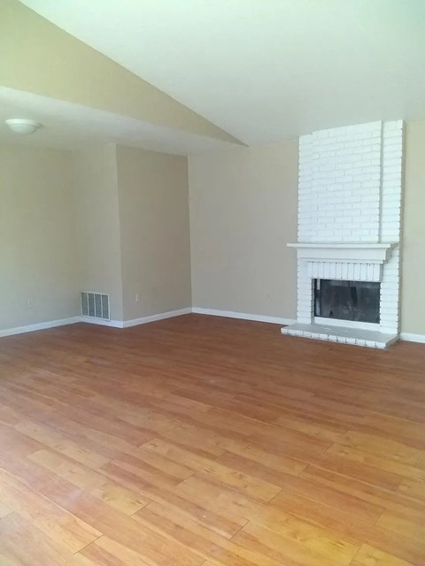 an empty living room with a fireplace and wooden floors