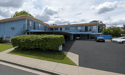 A blue building with a parking lot in front.