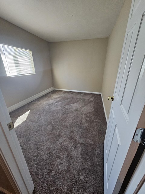 an empty bedroom with a carpeted floor and a window