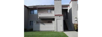the front of a gray house with a white door