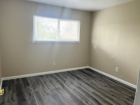 A room with a window and wooden flooring.