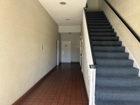 A hallway with a staircase on the right and a door on the left.