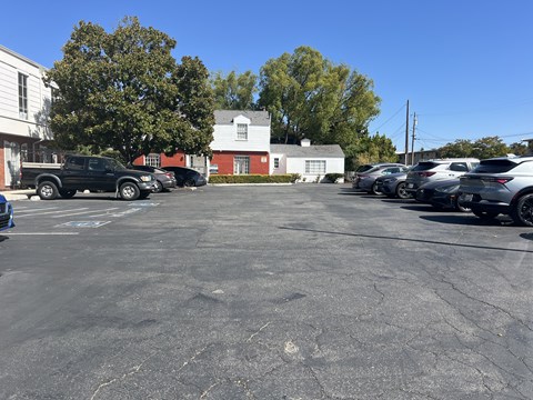 A parking lot with cars and a white building in the background.