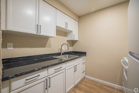 A kitchen with white cabinets and a black countertop.