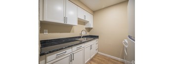 A kitchen with white cabinets and a black countertop.