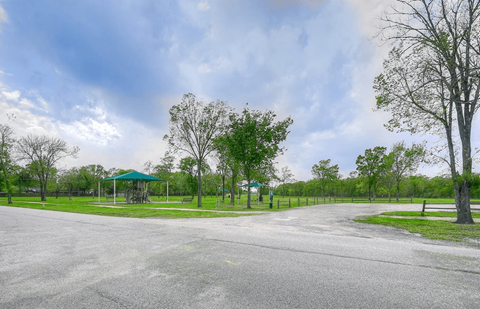 a road leading to a park with trees and a gazebo