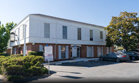 A white building with a parking lot in front.
