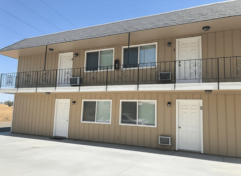 A beige building with a black railing and white doors.