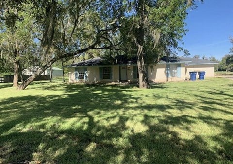 a house with a yard and trees in front of it