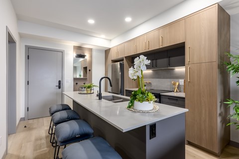 A modern kitchen with a long counter and bar stools.