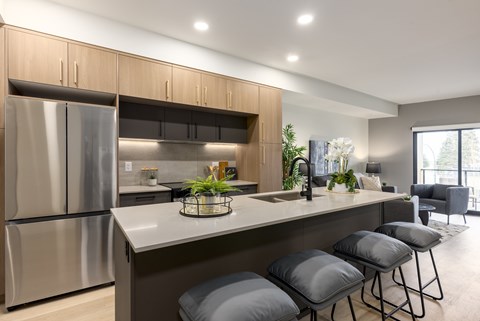 A modern kitchen with a stainless steel refrigerator and grey bar stools.