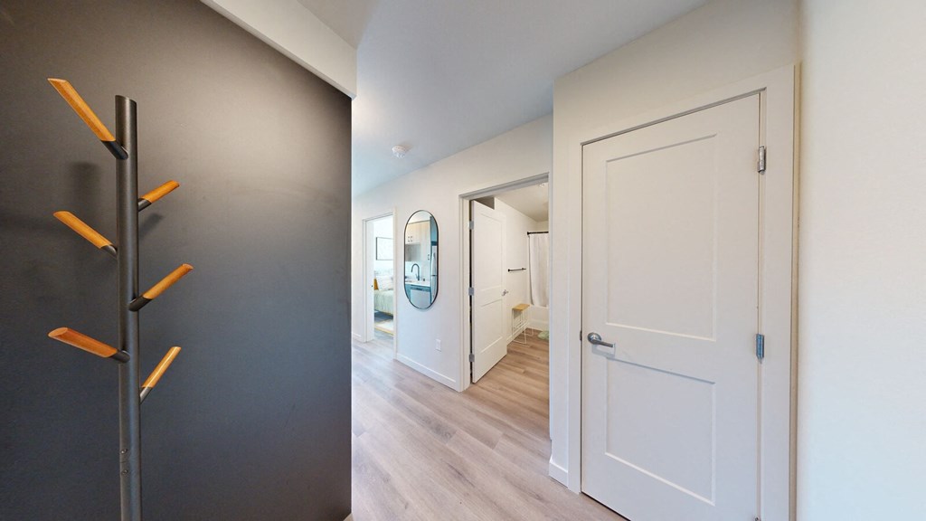 a door is open to a hallway with a hallway mirror and a hallway closet