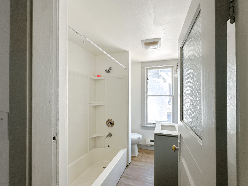 A white bathroom with a tub, toilet, and sink.