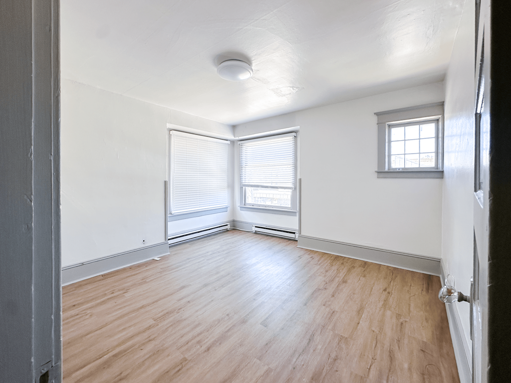 A room with wooden floors and a window with blinds.