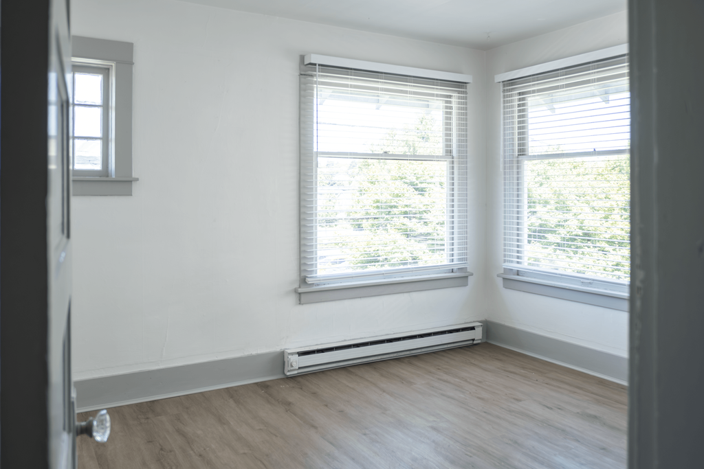 A room with a window and a heater on the floor.