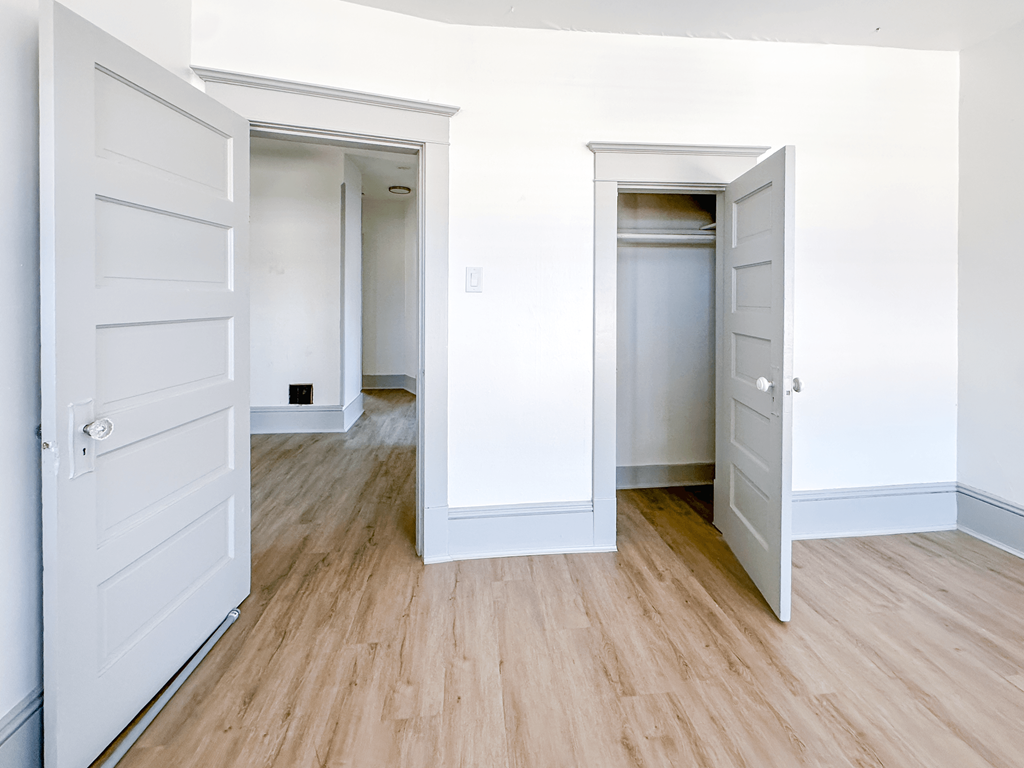 A room with two white doors and wooden floors.