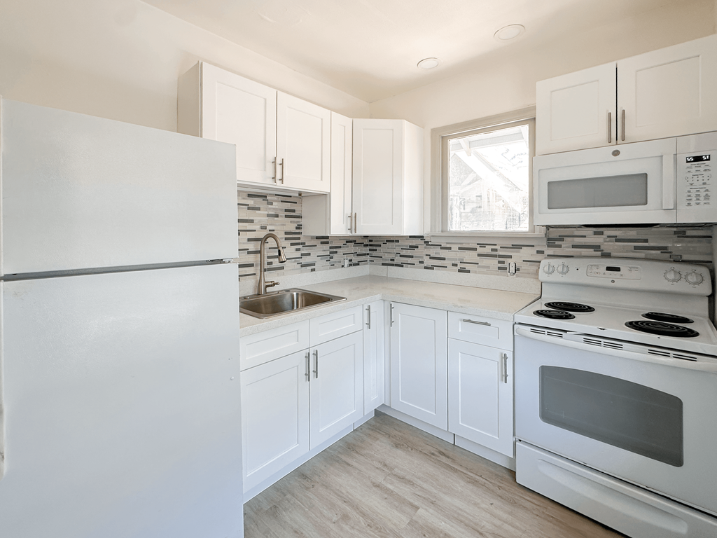 A kitchen with white appliances and cabinets.
