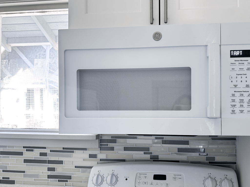 A white microwave oven with a tray in the middle and a control panel below it.