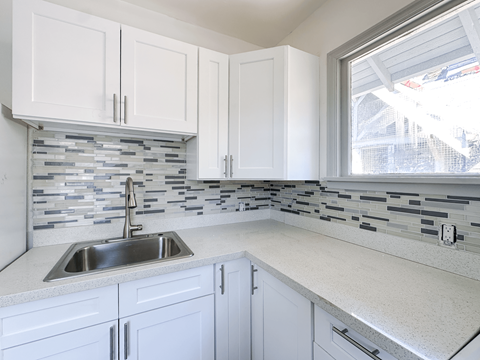 A kitchen with white cabinets and a silver sink.