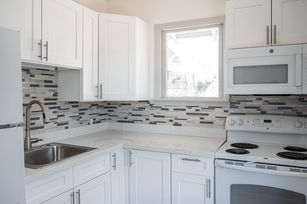 A kitchen with white cabinets and a white stove.