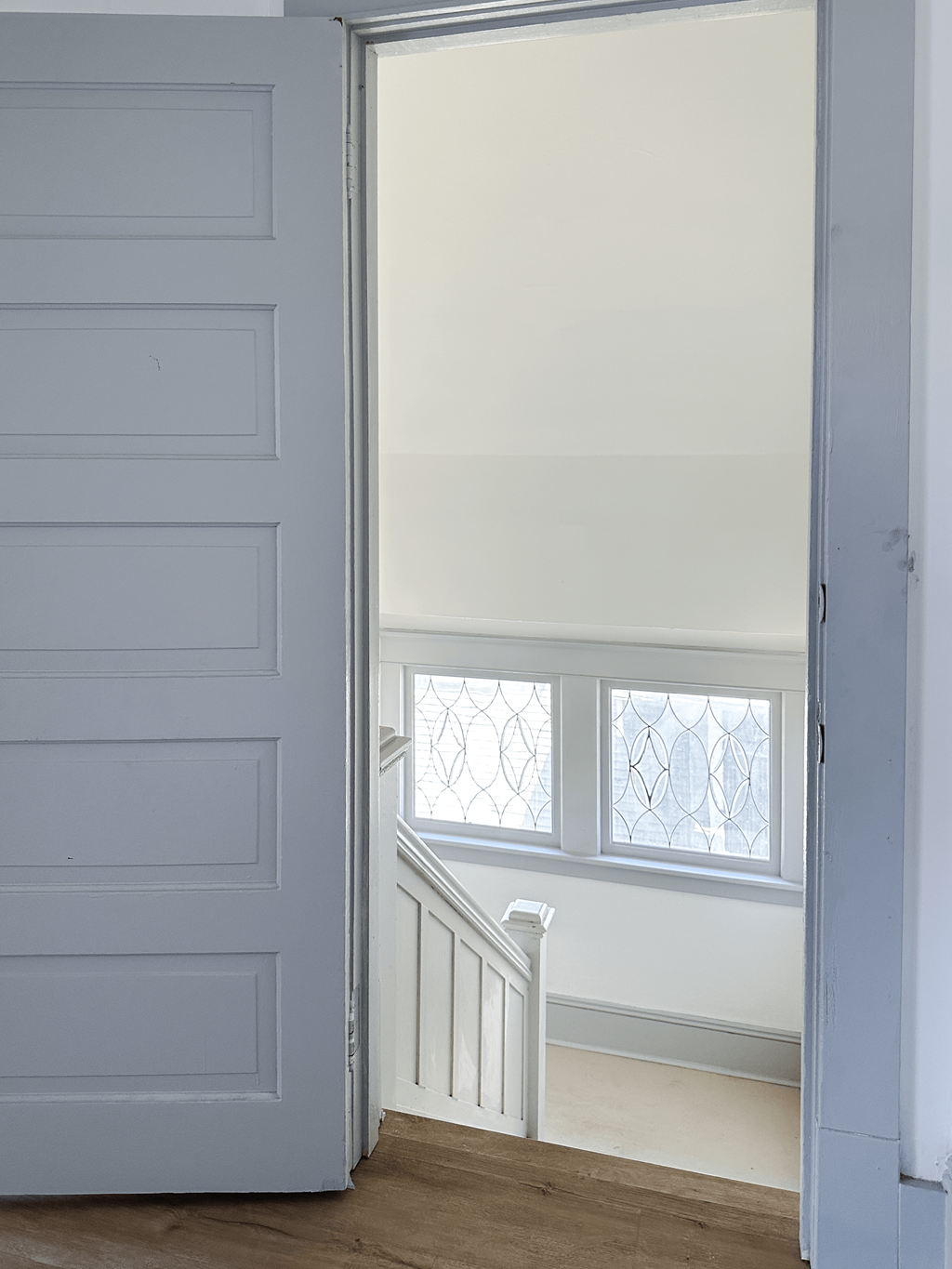 A white door is open to a hallway with a staircase.
