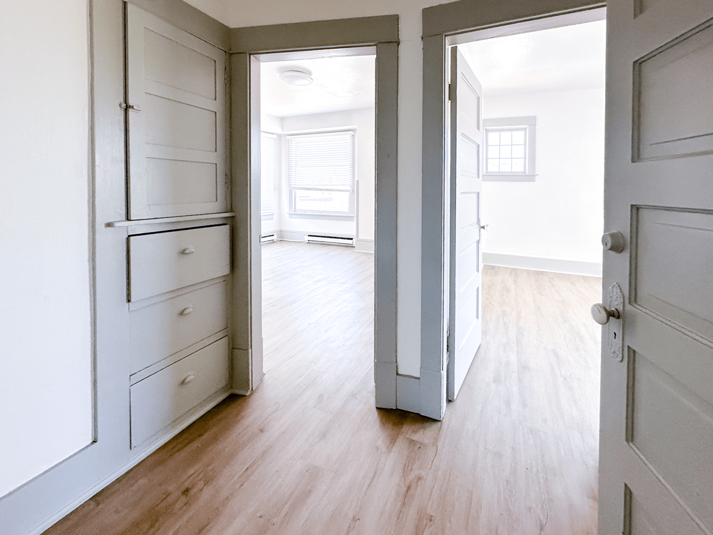 A white room with a wooden floor and a white door.