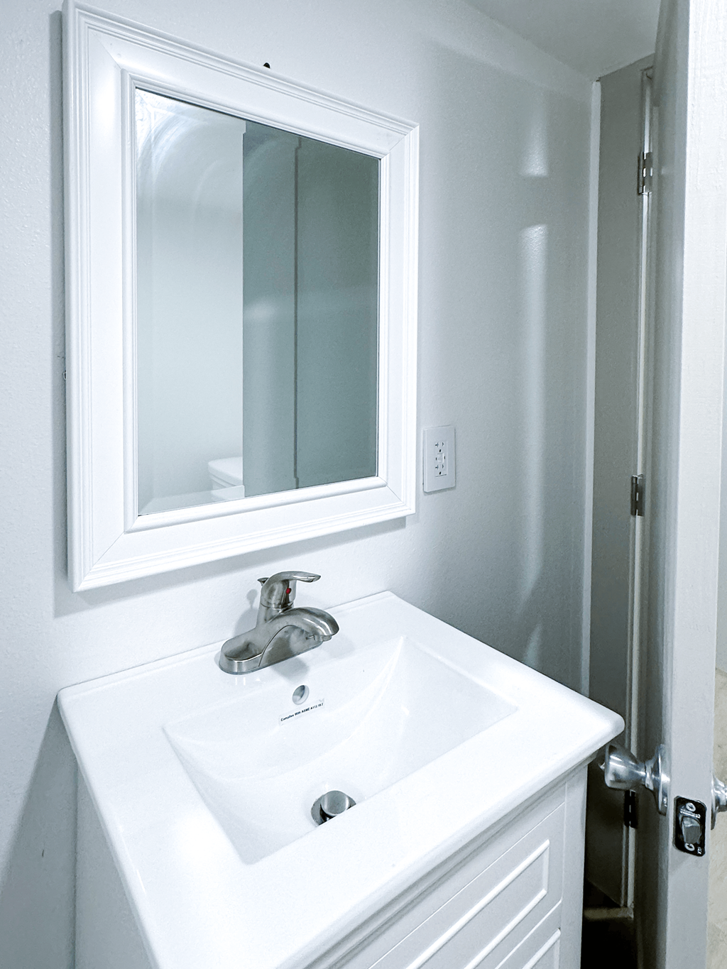 A white bathroom sink with a silver faucet and a mirror above it.