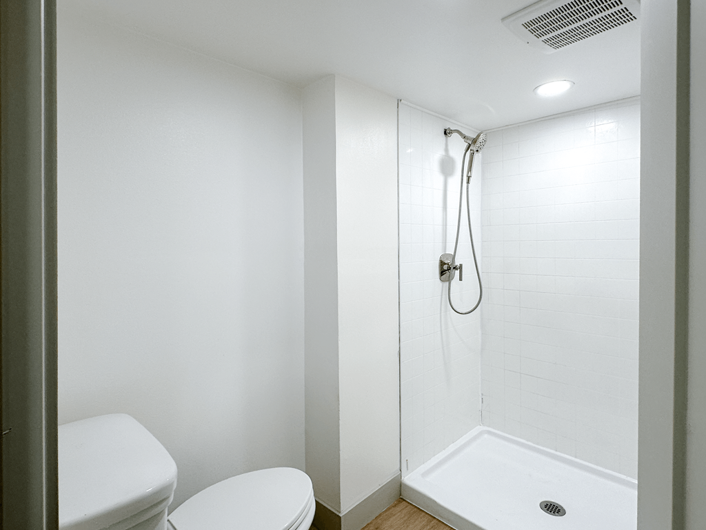 A white bathroom with a toilet and a walk in shower.