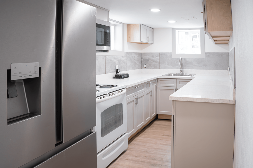 A modern kitchen with a stainless steel refrigerator and white appliances.