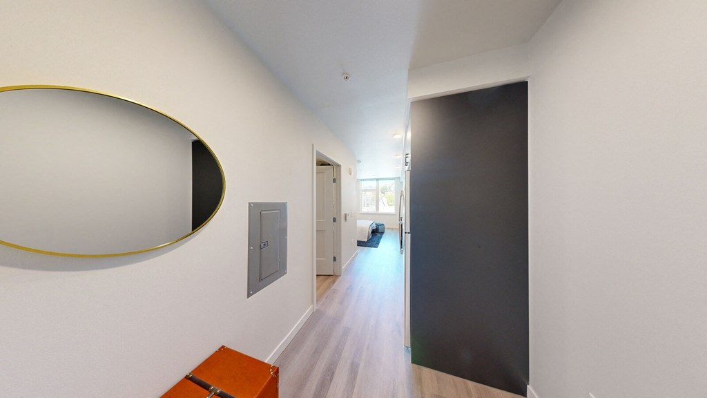 a hallway with a mirror on the wall and a black door