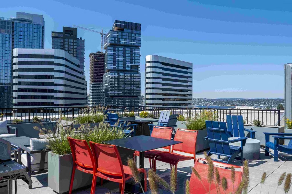 a rooftop terrace with tables and chairs and a view of the city