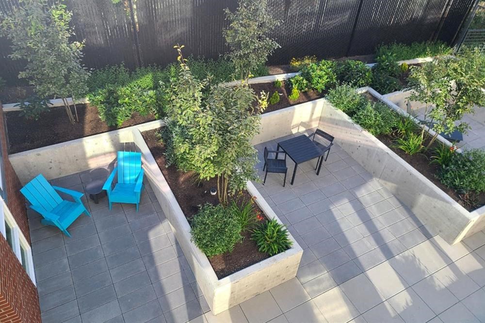 a patio with blue chairs and a table in a garden