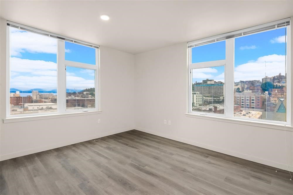 an empty room with three windows and a city view
