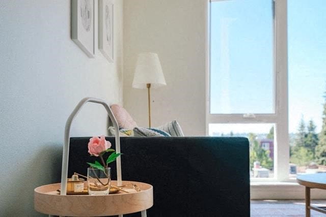 a living room with a black couch and a table with a flower