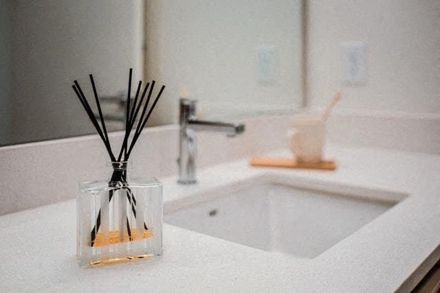 a bathroom sink with a vase with sticks in it