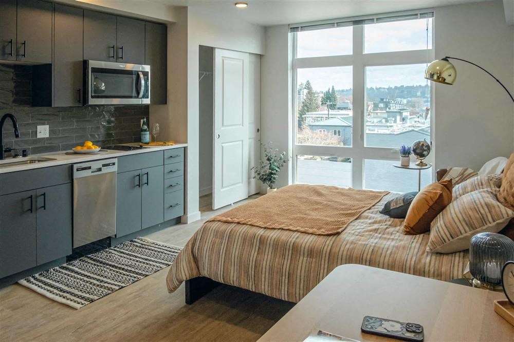 a bedroom with a kitchen and a large window