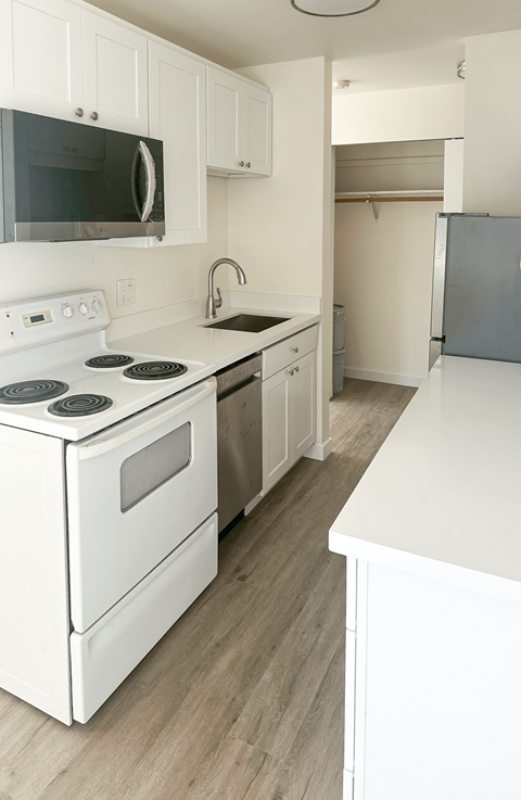 A white kitchen with a stove top oven and microwave.