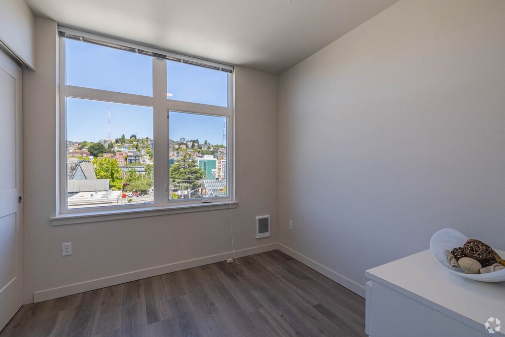 an empty living room with a large window and a city view