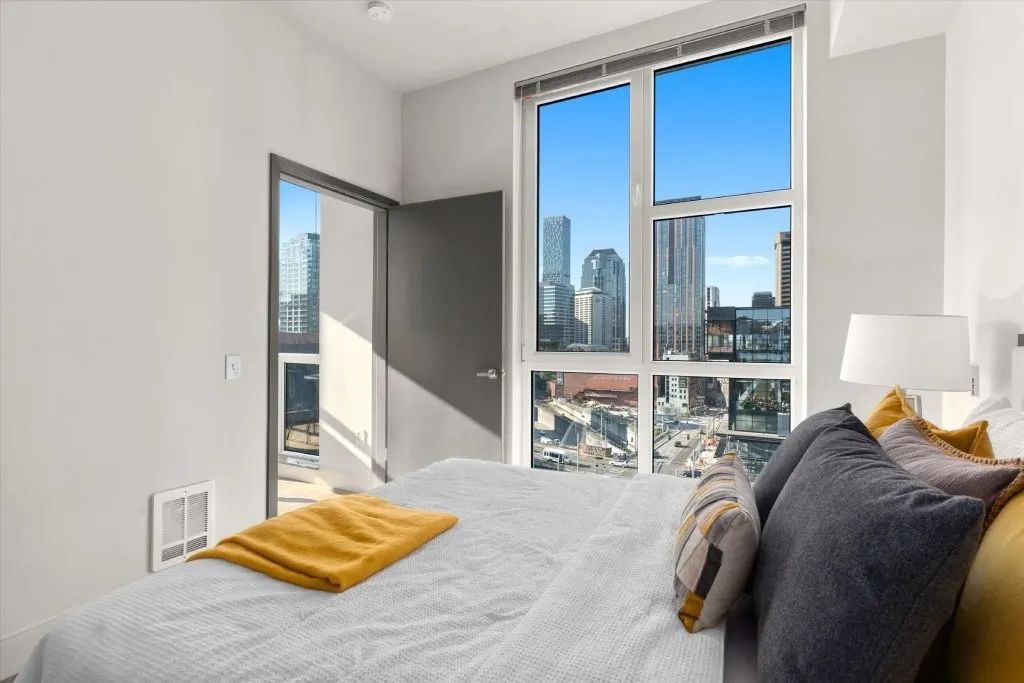 A bedroom with a large bed and a view of the city through the window.