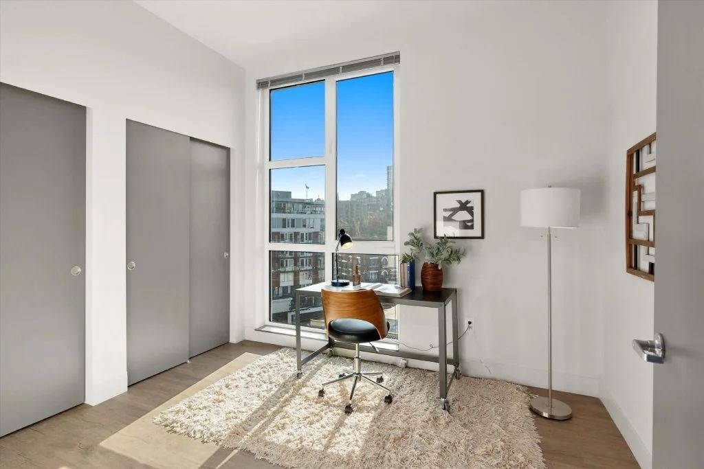 A room with a desk and a chair in front of a window with a view of a cityscape.