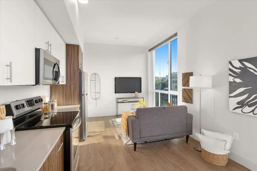 A modern kitchen with a grey couch and a flat screen TV.