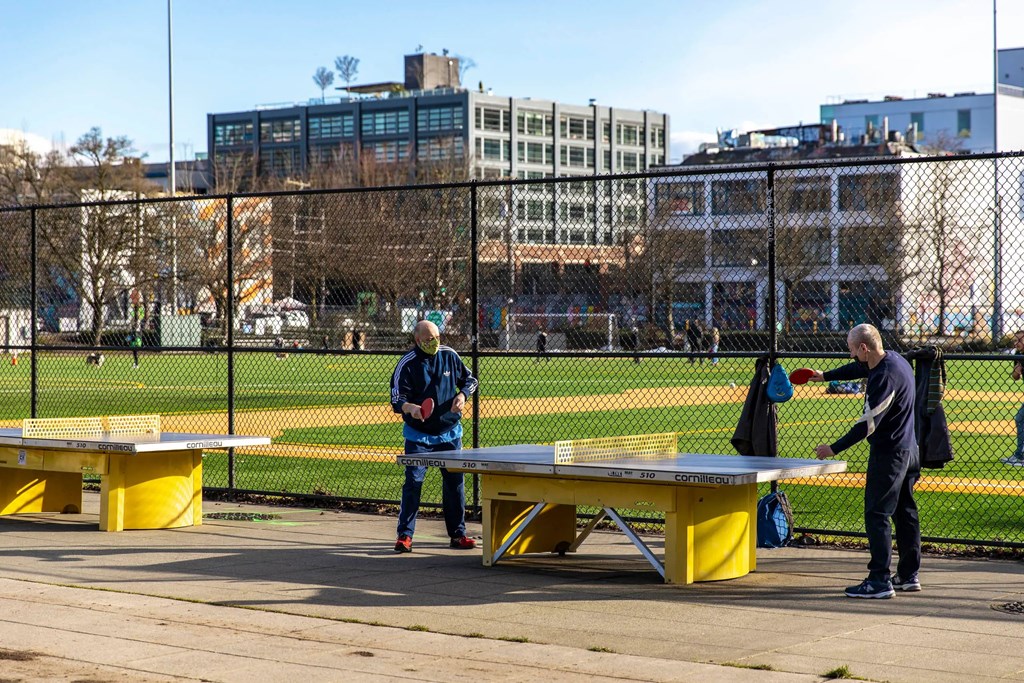 Two men playing ping pong in a park.