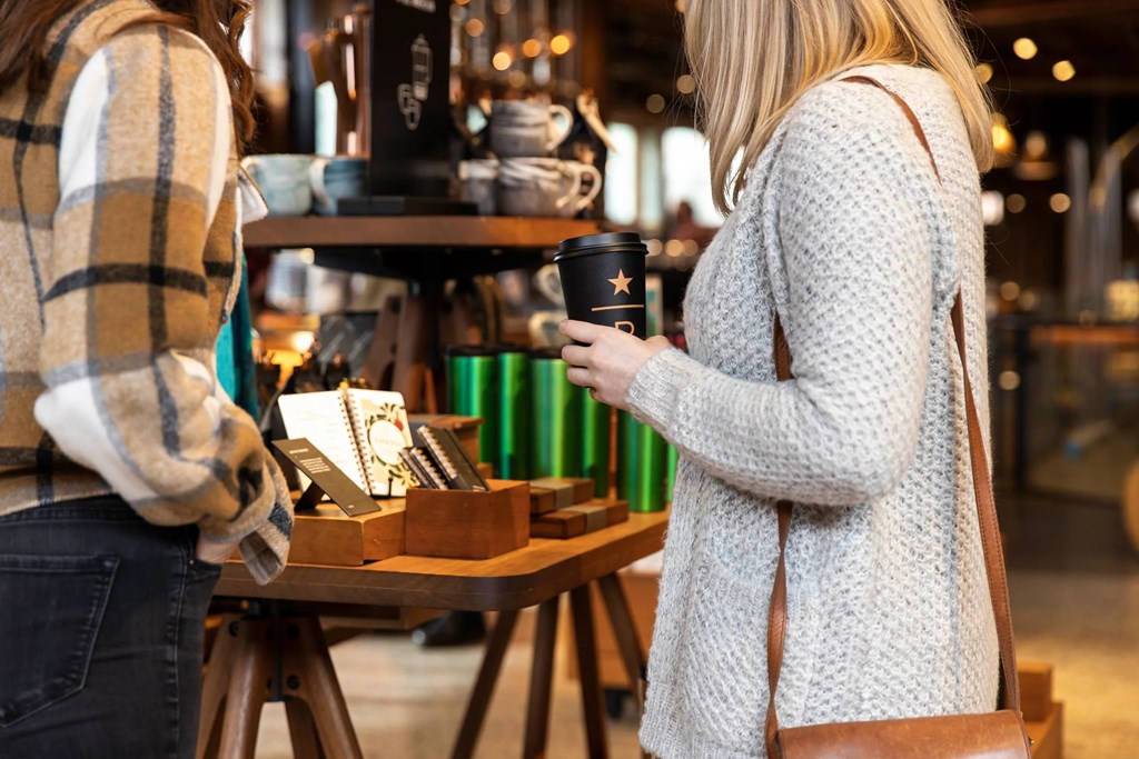 Two women in a coffee shop, one holding a coffee cup.