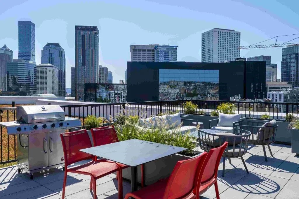 A rooftop patio with a table and chairs overlooking a city skyline.